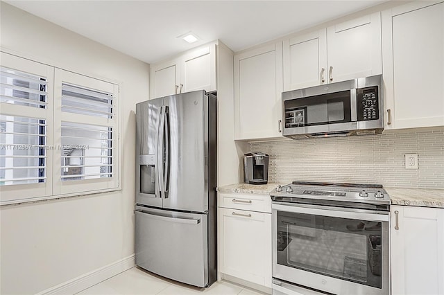 kitchen with white cabinets, decorative backsplash, light stone countertops, light tile patterned floors, and stainless steel appliances