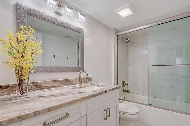 full bathroom featuring vanity, bath / shower combo with glass door, and toilet