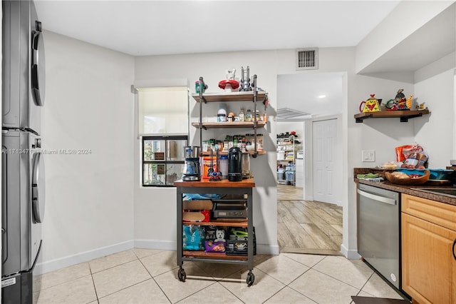 kitchen featuring stainless steel dishwasher, light tile patterned floors, and light brown cabinetry