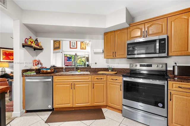 kitchen with dark stone countertops, light tile patterned floors, sink, and appliances with stainless steel finishes