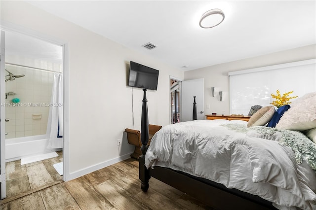 bedroom with hardwood / wood-style floors and connected bathroom