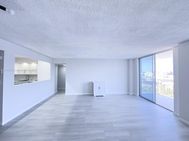 unfurnished room featuring a wall of windows and sink