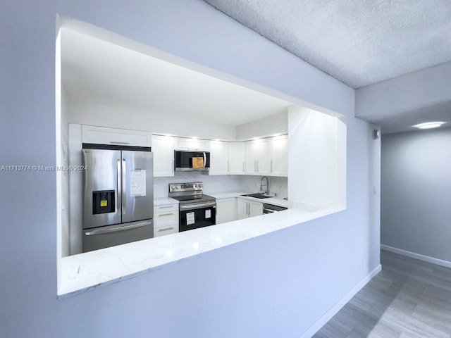 kitchen with white cabinetry, sink, a textured ceiling, appliances with stainless steel finishes, and light wood-type flooring