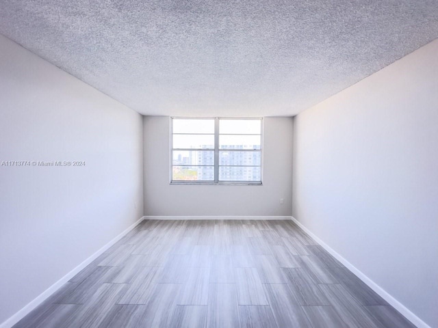 spare room featuring wood-type flooring and a textured ceiling