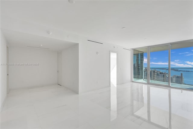 unfurnished room featuring a water view and a wall of windows