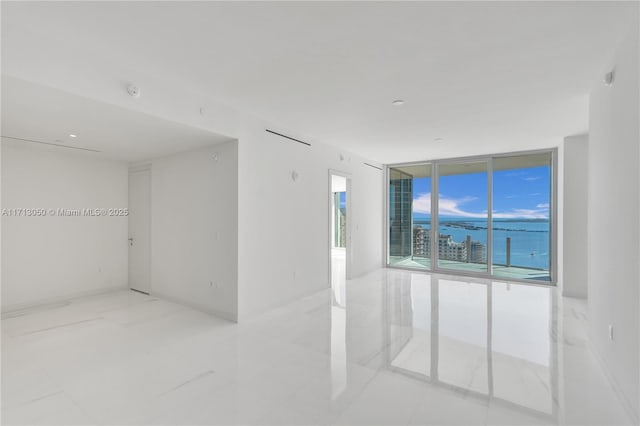 tiled empty room featuring a water view and expansive windows