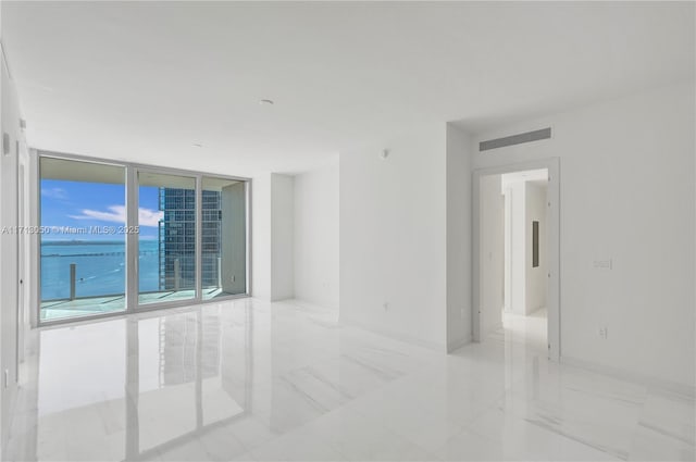 spare room featuring floor to ceiling windows and a water view