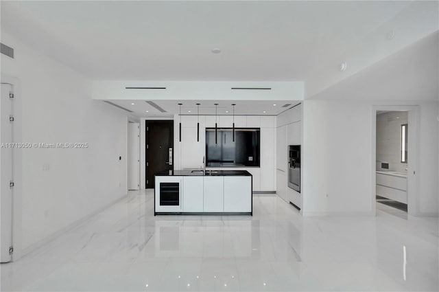 kitchen with sink, white cabinets, fridge, and multiple ovens