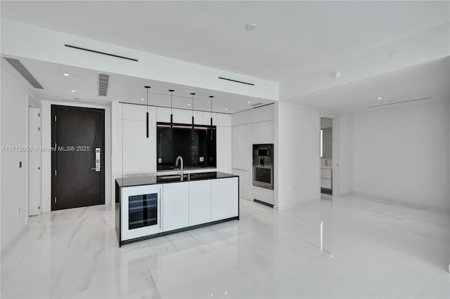 kitchen featuring sink, a kitchen island, wine cooler, oven, and white cabinets