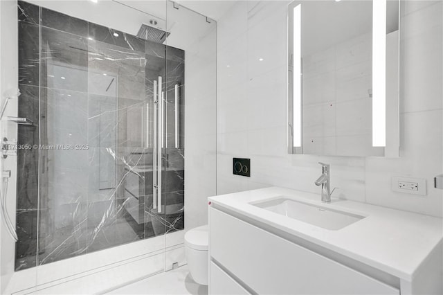 bathroom with a shower, vanity, tile walls, and toilet