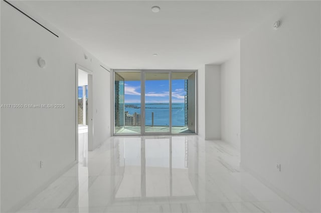 empty room featuring a water view and a wall of windows