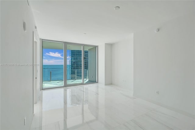 spare room with a water view and a wall of windows