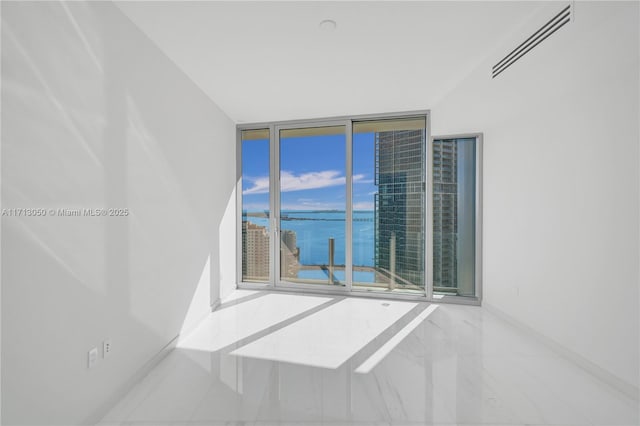 unfurnished room featuring floor to ceiling windows and a water view