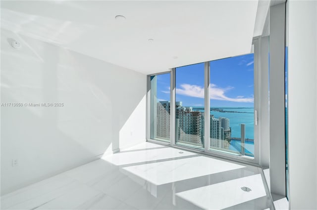 empty room featuring expansive windows, plenty of natural light, and a water view