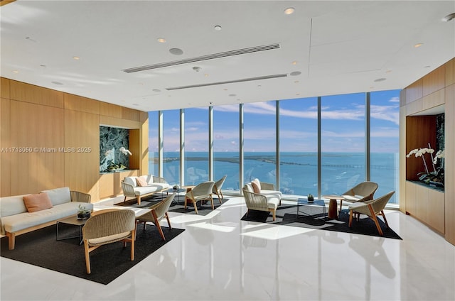 living room featuring wood walls, a water view, and a wall of windows