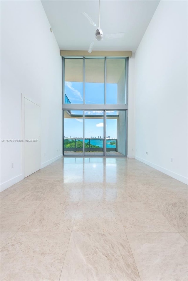 spare room with floor to ceiling windows and ceiling fan