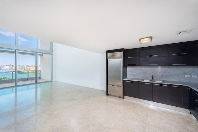 kitchen featuring a water view, tasteful backsplash, built in fridge, and sink