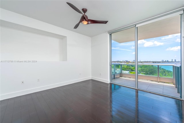 unfurnished room with ceiling fan, dark hardwood / wood-style floors, and a wall of windows