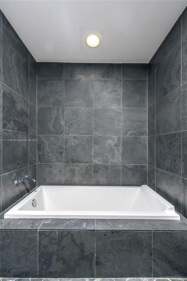 bathroom with tile walls and tiled tub