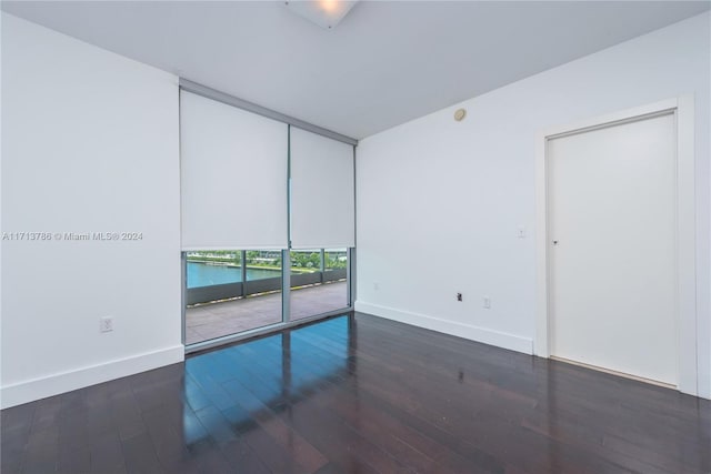 spare room featuring a water view and dark hardwood / wood-style floors