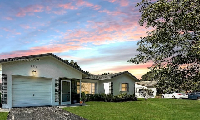 ranch-style house with a garage and a yard