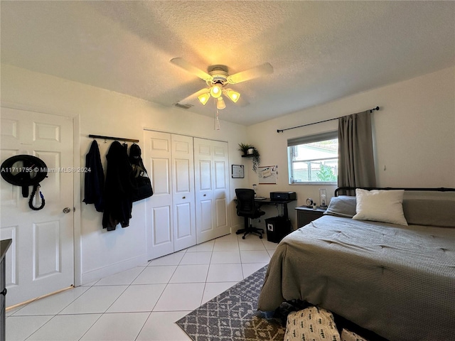 bedroom featuring light tile patterned floors, a textured ceiling, a closet, and ceiling fan