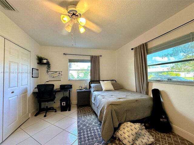 bedroom with ceiling fan, light tile patterned flooring, and a closet