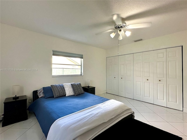 tiled bedroom with ceiling fan, a closet, and a textured ceiling