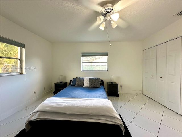 bedroom featuring a textured ceiling, a closet, ceiling fan, and light tile patterned flooring