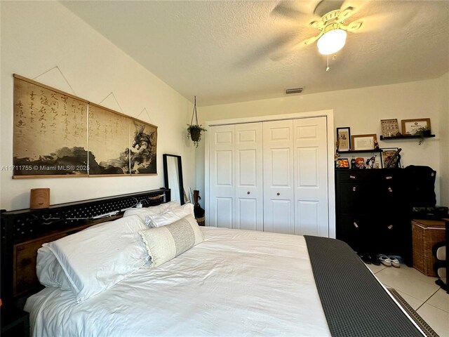 tiled bedroom featuring ceiling fan, a closet, and a textured ceiling