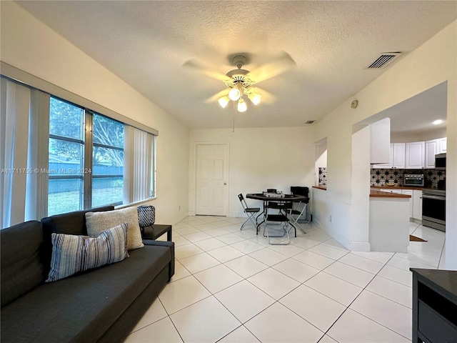 tiled living room with ceiling fan and a textured ceiling