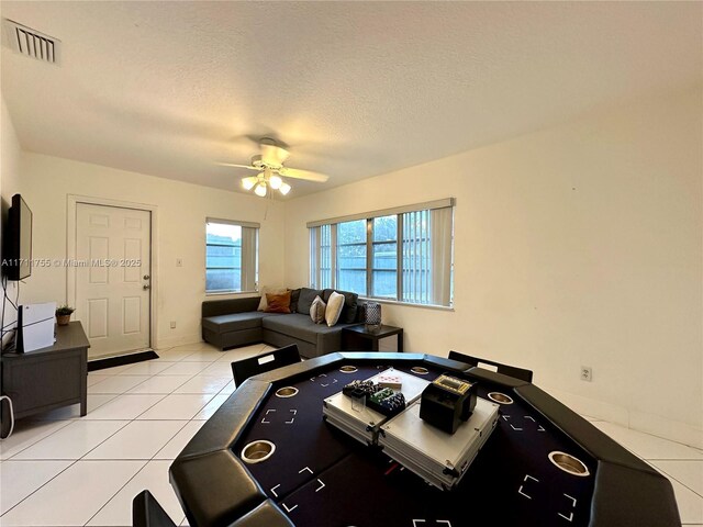 living room featuring light tile patterned floors, a textured ceiling, and ceiling fan