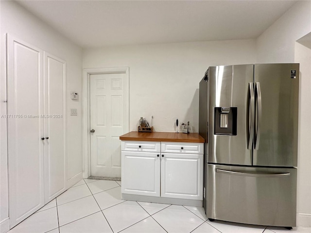 kitchen featuring wooden counters, stainless steel fridge, white cabinets, and light tile patterned floors