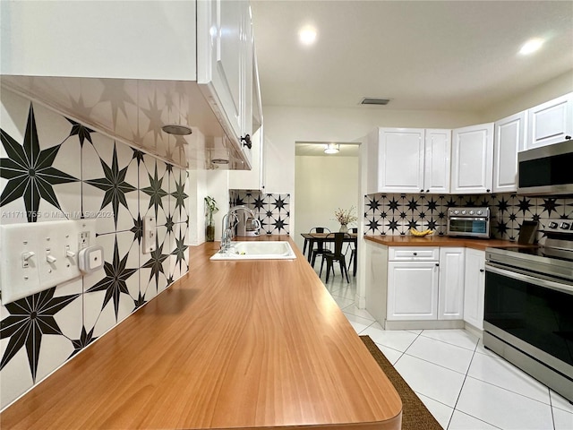 kitchen featuring white cabinets, sink, appliances with stainless steel finishes, tasteful backsplash, and light tile patterned flooring