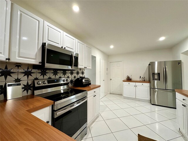 kitchen with wooden counters, stainless steel appliances, and white cabinets