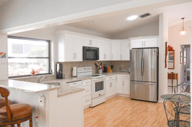 kitchen featuring white cabinets, stainless steel fridge, vaulted ceiling, and electric stove