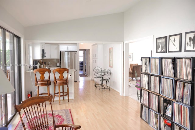 interior space featuring a kitchen bar, kitchen peninsula, light hardwood / wood-style flooring, white cabinets, and stainless steel refrigerator