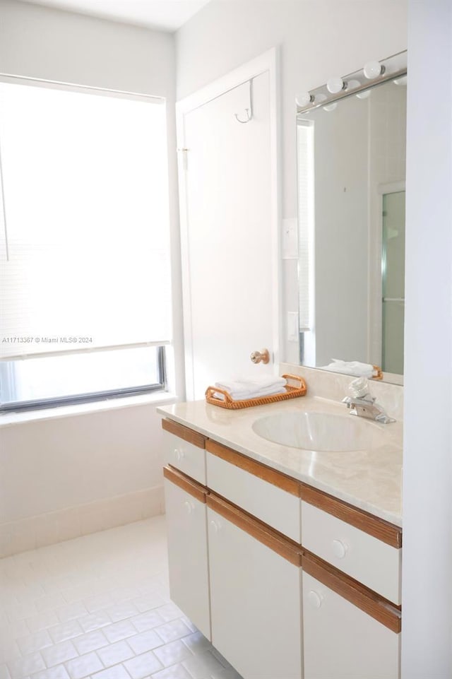 bathroom with tile patterned flooring, vanity, and a healthy amount of sunlight