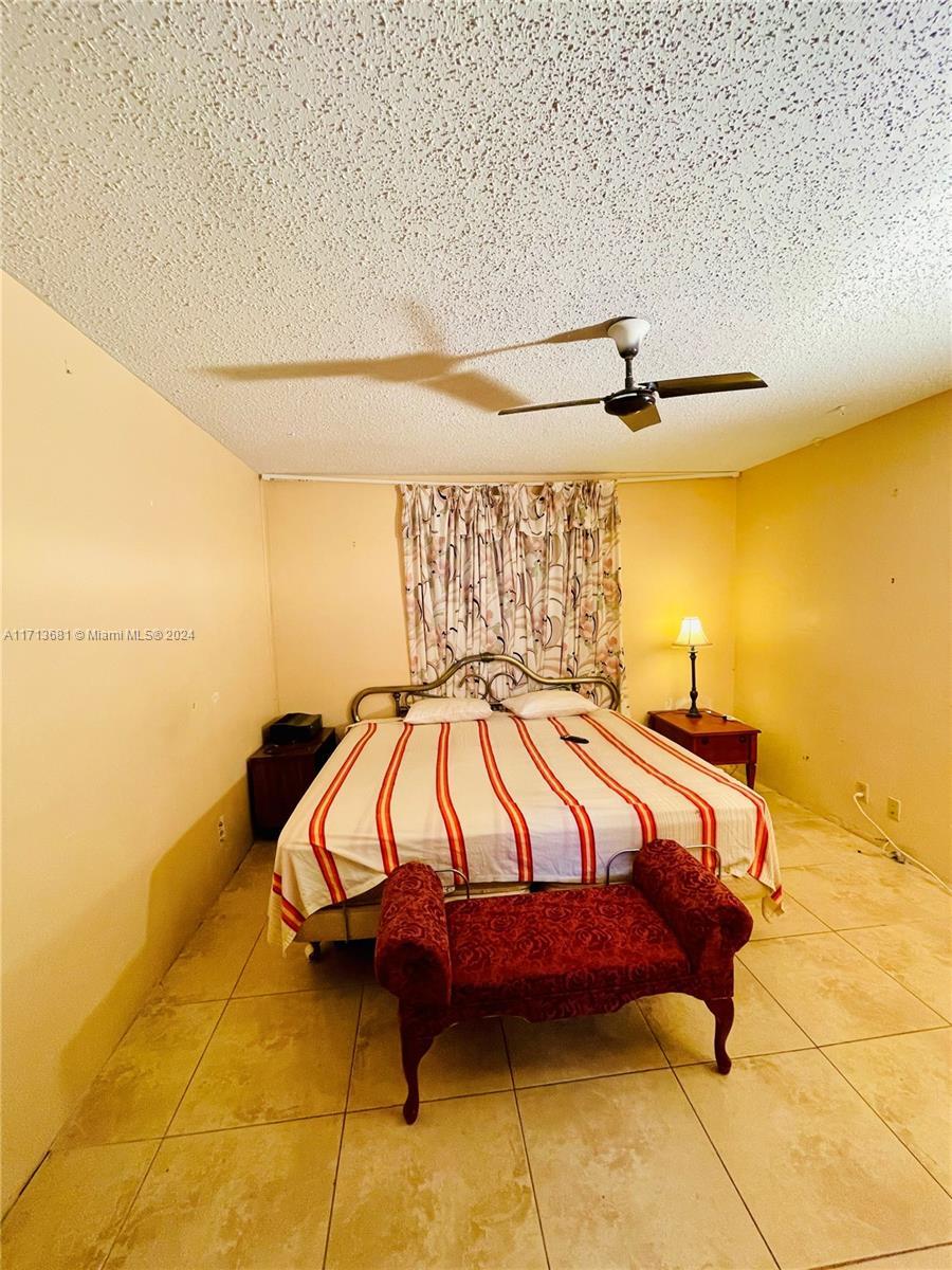 bedroom with ceiling fan, tile patterned flooring, and a textured ceiling