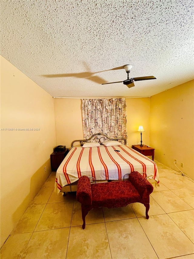 bedroom with ceiling fan, tile patterned flooring, and a textured ceiling