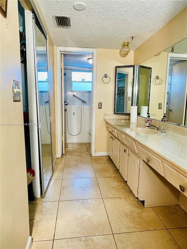 bathroom featuring tile patterned flooring, vanity, and a textured ceiling