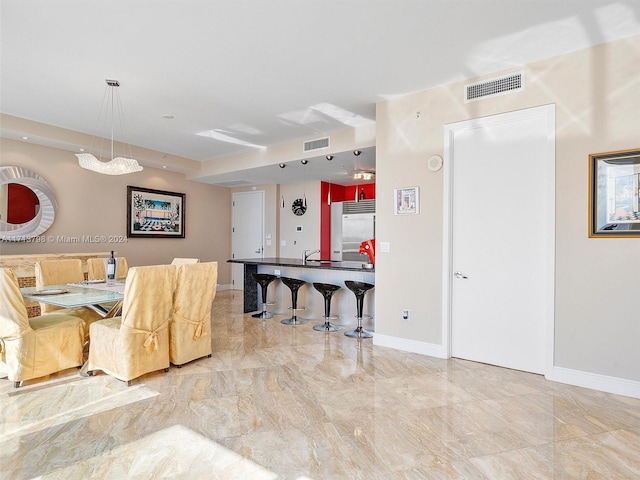 kitchen with decorative light fixtures, built in refrigerator, and sink