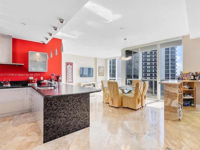 kitchen featuring a center island with sink, expansive windows, sink, range hood, and gas cooktop