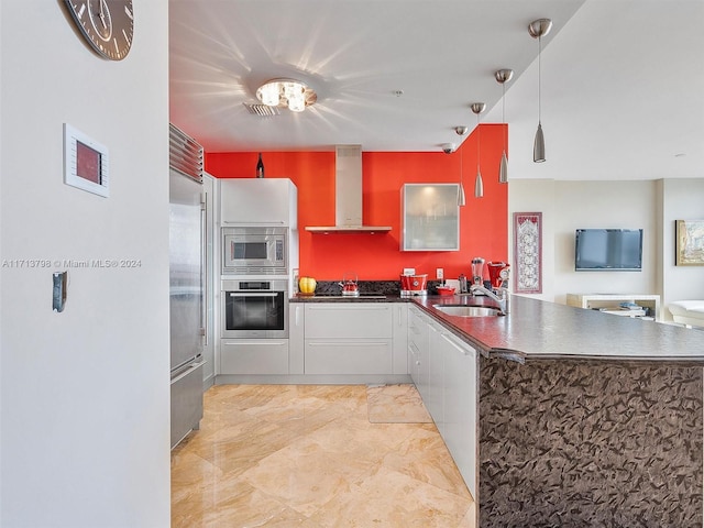 kitchen with kitchen peninsula, built in appliances, sink, and wall chimney range hood