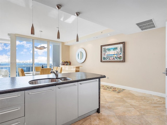 kitchen featuring sink, a water view, and hanging light fixtures