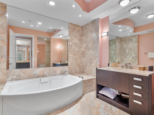 bathroom featuring vanity, tile walls, and tiled tub