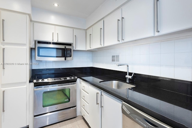 kitchen with sink, dark stone counters, decorative backsplash, white cabinets, and appliances with stainless steel finishes