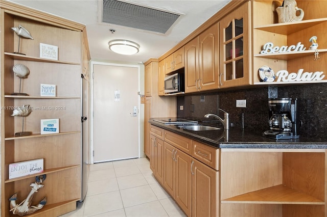 kitchen featuring decorative backsplash, sink, light tile patterned floors, and dark stone counters