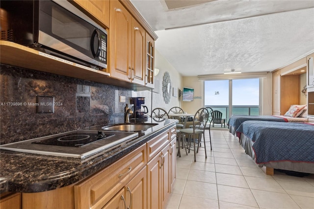 kitchen featuring sink, light tile patterned floors, a textured ceiling, tasteful backsplash, and electric stovetop