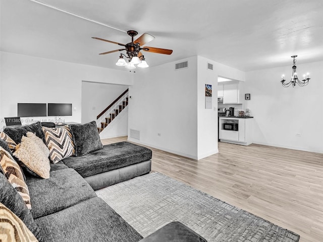 living room with ceiling fan with notable chandelier and light wood-type flooring